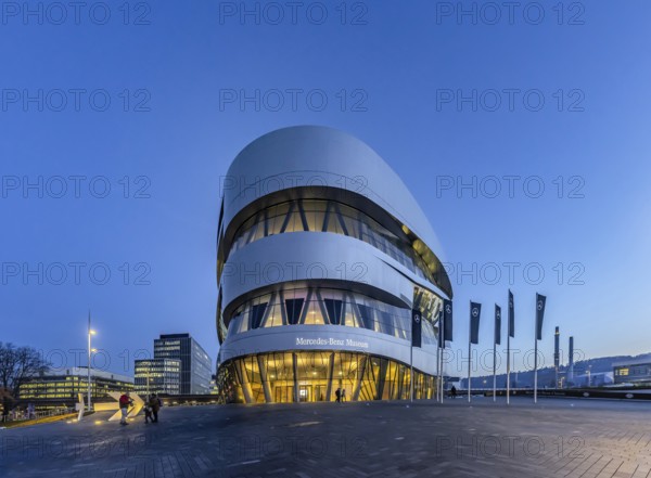 The Mercedes-Benz Museum in Stuttgart presents a journey through the automotive history of the global corporation. Spectacular architecture of the Automobile Museum in the evening. On the left, the headquarters of Mercedes-Benz Group AG. Untertürkheim, Stuttgart, Baden-Württemberg, Germany