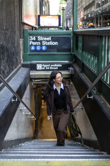 Young businesswoman ascending the stairs from the new york city subway at 34 street penn station, demonstrating urban commute, independence, and career drive in manhattan