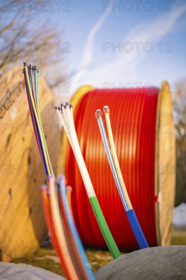 Colourful cables in a wintry environment in front of large, red cable spools, fibre-optic groundbreaking, Freudenstadt, Germany