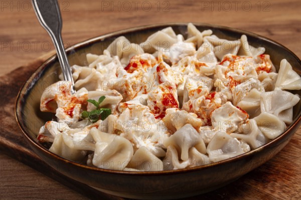 The dish features a generous serving of Turkish dumplings topped with velvety yogurt and a drizzle of spicy red sauce