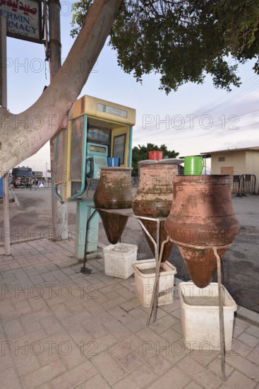 Telephone box and clay carafes with drinking water, Esna, Egypt