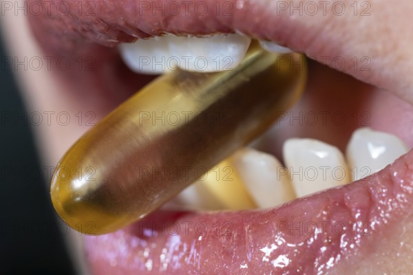 Close view of a woman mouth taking an omega 3 capsule