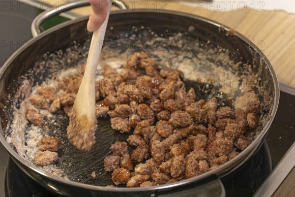Almonds caramelized in a pan while stirred with a spoon. Germany