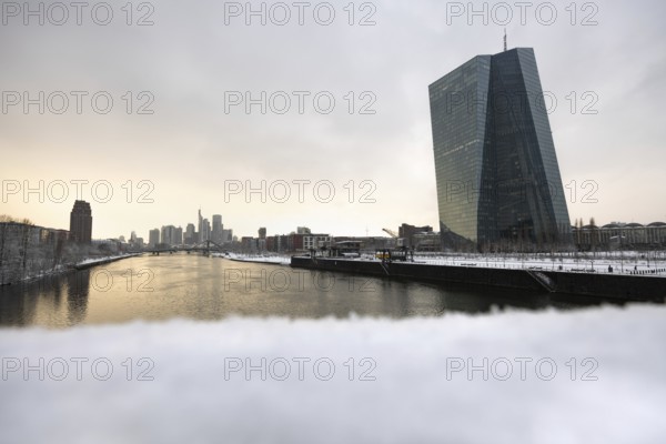 Snow lies along the banks of the Main from the European Central Bank (ECB) to the Frankfurt banking skyline, Osthafen, Frankfurt am Main, Hesse, Germany