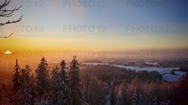A wintry sunset over a snow-covered forest with glowing sky, Frankenwald nature park Park, Upper Franconia, Germany