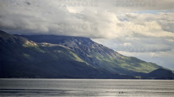 Dramatic mountain landscape with cloudy sky and calm lake in the foreground, Lake Ohrid, North Macedonia