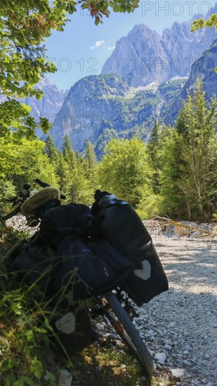 A bicycle on a dirt road in an alpine landscape with mountains and forests in the background, Slovenia