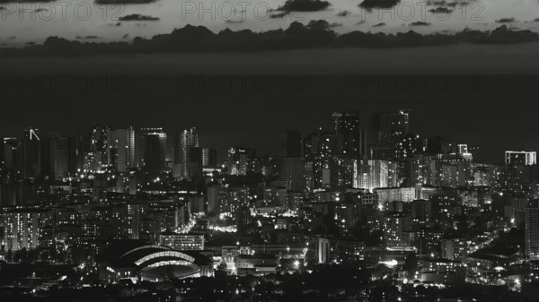 City view at night with illuminated skyscrapers and clouds in the sky in black and white, Batumi, Georgia