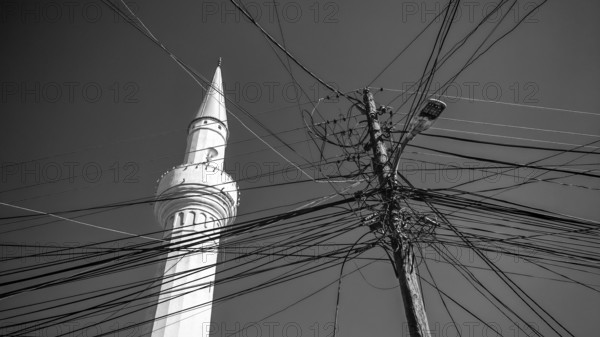 A minaret and numerous power lines against a monochrome sky, Prizren, Kosovo