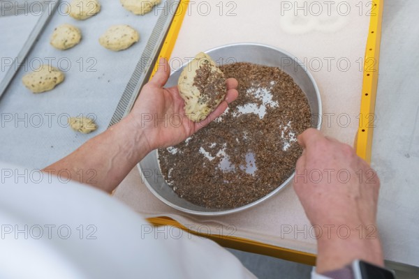 A baker sprinkles a dough with linseed on a baking tray, bake rolls, Haselstaller Hof, Gechingen, Germany