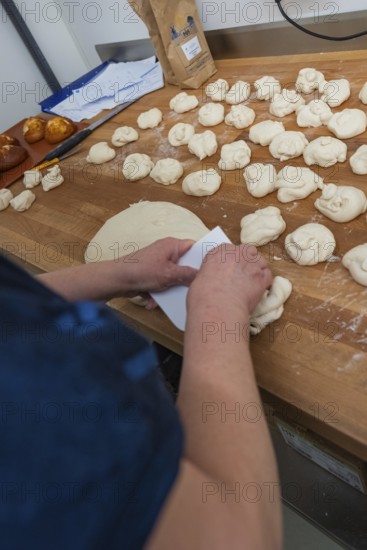 A baker kneads dough on a wooden work surface in the bakery, baking rolls, Haselstaller Hof, Gechingen, Germany