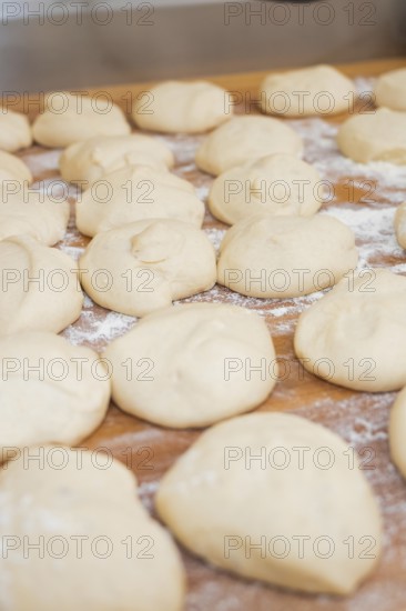 Unbaked dough balls with flour on wooden table to prepare for baking, baking rolls, Haselstaller Hof, Gechingen, Germany
