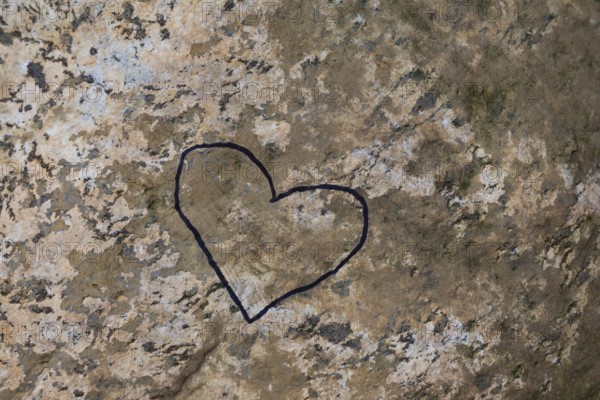 Close-up of painted black heart outline symbol on tanned nuanced rock surface, Quebec, Canada