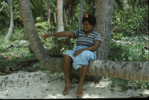 Woman sitting on a coconut log on the beach, Tavewa Island, Yasawa Islands, Fiji