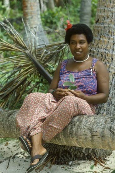 Woman (Katherina) sitting on a coconut trunk on the beach, Tavewa Island, Yasawa Islands, Fiji
