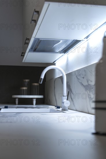 Minimalist kitchen corner with white worktop and illuminated back wall