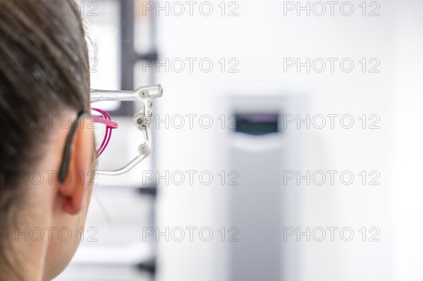 Woman looking through glasses at a vision device in an optician environment, optician, Pforzheim