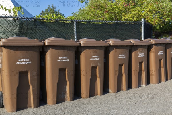 Row of brown plastic heavy duty portable composting bins for depositing organic materials and leftover foods at outdoor public recycling site, Quebec, Canada