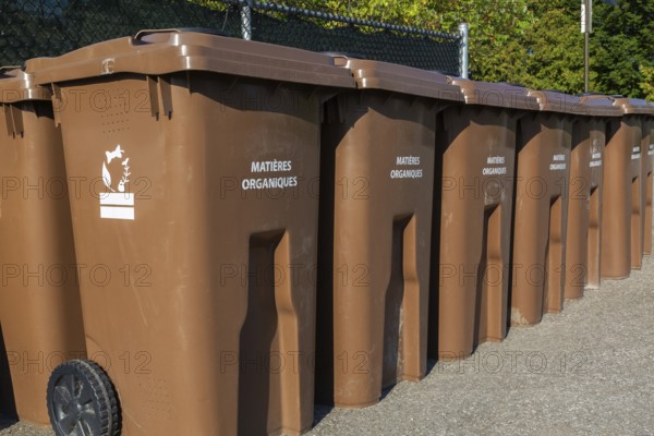 Rows of brown plastic heavy duty portable composting bins for depositing organic materials and leftover foods at outdoor public recycling site, Quebec, Canada