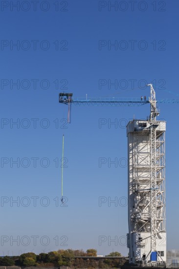 Montreal Bungee Tower with male bungee jumper in midair with his ankles tied to a long yellow elastic bungee jumping cord, Old Port of Montreal, Quebec, Canada