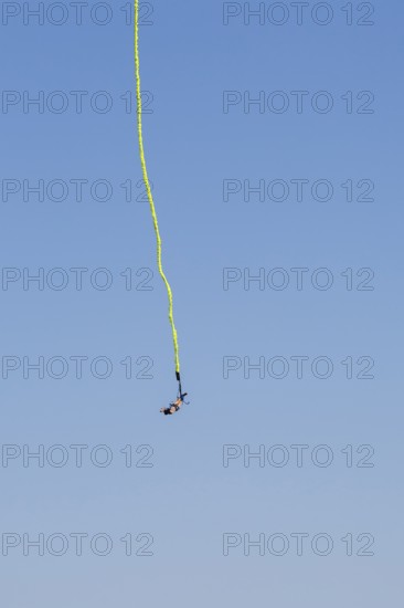 Female bungee jumper in midair with her ankles tied to a long yellow elastic bungee jumping cord, Montreal Bungee site, Old Port of Montreal, Quebec, Canada