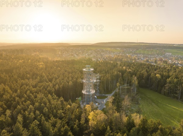 A tower towers over a forest, the view extends to a city in warm sunset light, Himmelsglück observation tower with Flying Fox, Schömberg, Black Forest, Germany