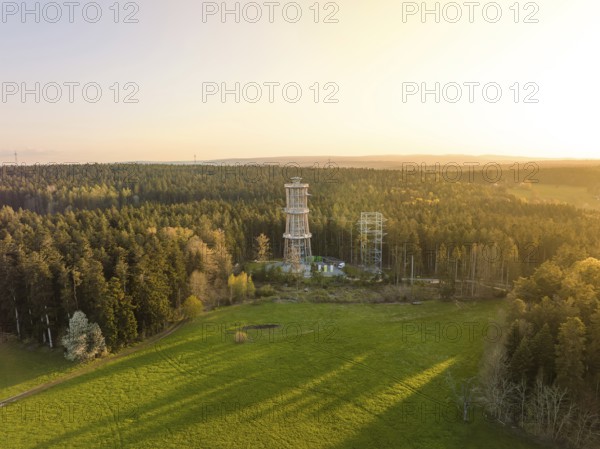 A tower stands in the middle of a forest next to a meadow, illuminated by warm sunlight, Himmelsglück observation tower with flying fox, Schömberg, Black Forest, Germany