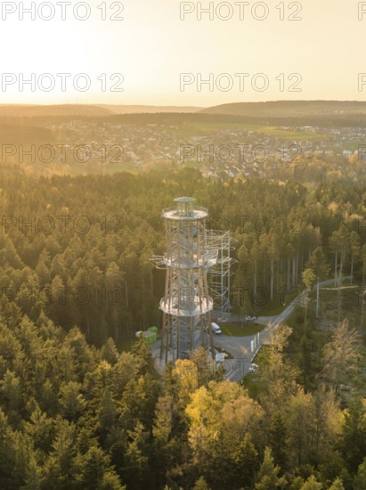 An observation tower towers over the treetops of a forest, with a city in the background and sunset, Himmelsglück observation tower with Flying Fox, Schömberg, Black Forest, Germany