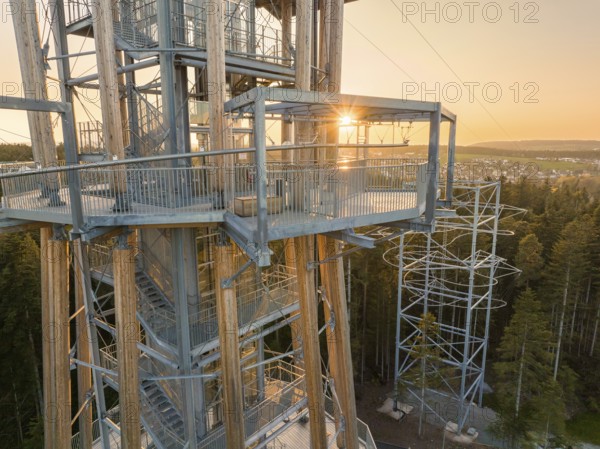 A wooden observation tower with metal structures at sunset, framed by a green forest, observation tower Himmelsglück with Flying Fox, Schömberg, Black Forest, Germany