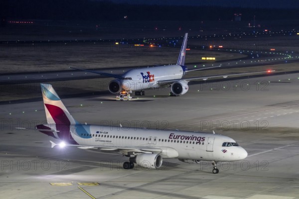 FedEx Boeing 777-FS2 cargo plane is towed to take off, at Cologne/Bonn airport, Eurowings aircraft on the taxiway to the terminal, North Rhine-Westphalia, Germany