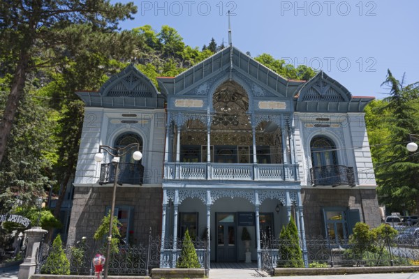 Magnificent historical architecture with an ornate blue veranda nestled in green nature, old villa of Mirza-Riza-Khan from the 19th century, cultural monument, Golden Tulip Borjomi resort, Borjomi, Kura river, Samtskhe—Javakheti region, Lesser Caucasus, Georgia