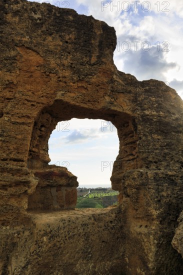 Arkosolium path, necropolis, view through arched niche on coastline and the sea, burial chamber, carved into the rock, wall, Valley of the Temples, Agrigento, Sicily, Italy