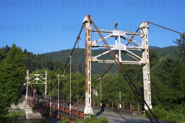 Old suspension bridge stretches across a river surrounded by green landscape, suspension bridge across the Kura River near Kortaneti, Samtskhe—Javakheti region, Georgia