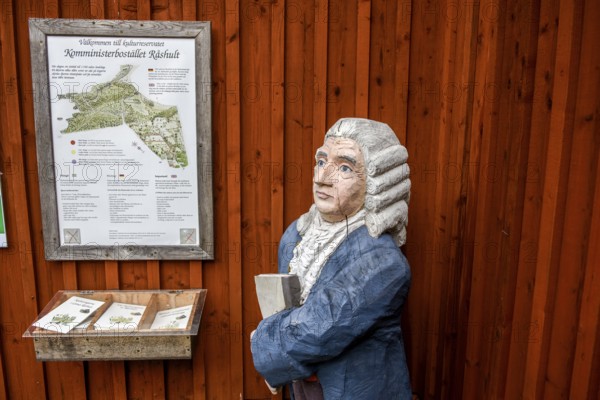 Wooden statue of botanist and founder of the binary nomenclature Carl von Linné with white hair and blue jacket in front of a wooden wall, Linnés Råshult, Älmhult, Kronobergs län, Småland, Sweden