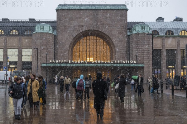 Busy side entrance to Central Station with Christmas decoration during snowfall, Helsinki, Finland
