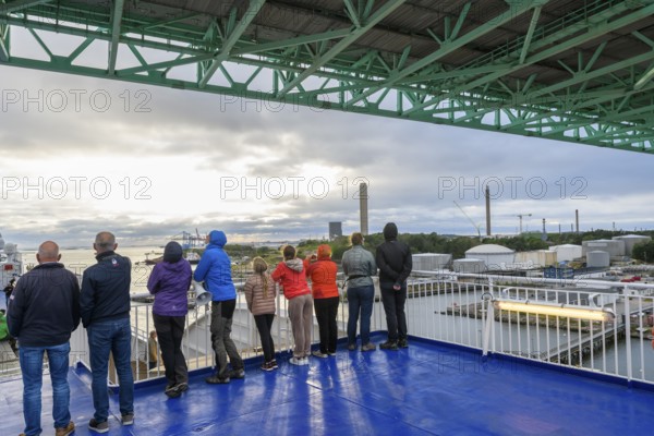 Group of people on a ship deck looking at the harbor crossing under the Älvsborgsbron suspension bridge under a cloudy sky on a ferry boat, Stena Line Gothenburg-Kiel, Gothenburg, Västra Götalands län, Sweden