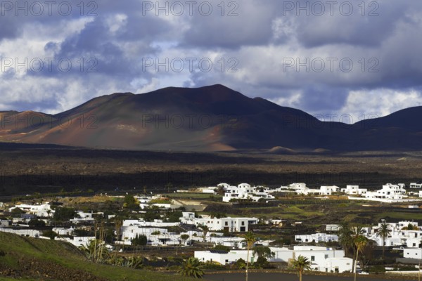 Partial view of the municipality of Yaiza at the foot of volcanic mountains under dramatic clouds in Lanzarote, Yaiza Lanzarote