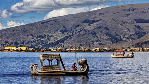 Two reed boats on a lake surrounded by mountains and a clear sky, The floating reed islands of the Uros in Lake Titicaca in Peru
