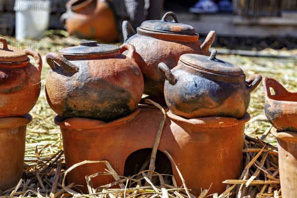 Clay pots and cooking areas arranged on a straw bed with rustic charm, The floating reed islands of the Uros in Lake Titicaca in Peru