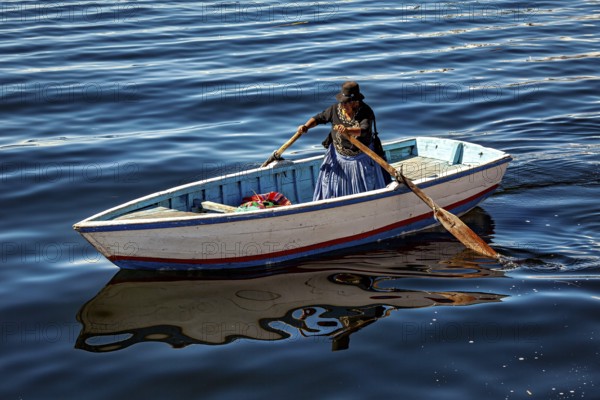 Woman rowing in a traditional boat on the calm waters of the lake, The floating reed islands of the Uros in Lake Titicaca in Peru