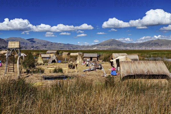 Reed village surrounded by mountains and under a clear blue sky, The floating reed islands of Uros in Lake Titicaca in Peru