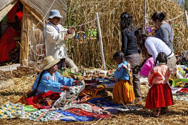 People and children sell and look at crafts in a village made of straw huts, the floating reed islands of the Uros in Lake Titicaca in Peru