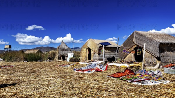 Traditional thatched huts on an island under a clear sky, The floating reed islands of the Uros in Lake Titicaca in Peru