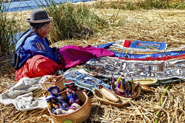 Woman sitting at colorful crafts on an island near a lake, The floating reed islands of Uros in Lake Titicaca in Peru