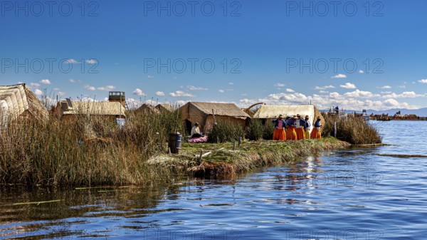 Reed huts on an island in the lake with people wearing colorful traditional clothing, The floating reed islands of the Uros in Lake Titicaca in Peru