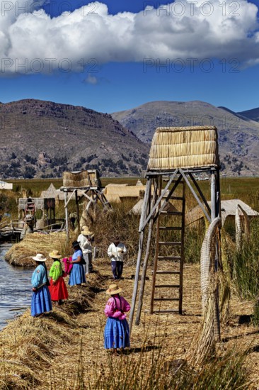 Women in traditional clothing at an elevated point overlooking the water, The floating reed islands of the Uros in Lake Titicaca in Peru