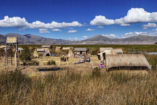 Extensive reed village in a natural setting with mountains, the floating reed islands of the Uros in Lake Titicaca in Peru