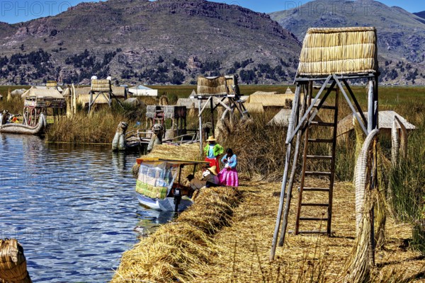 Handmade boats and huts on a lake surrounded by natural scenery, The floating reed islands of the Uros in Lake Titicaca in Peru