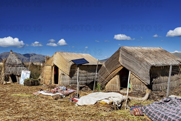 Traditional reed huts with solar panels on a lake surrounded by mountains, The floating reed islands of the Uros in Lake Titicaca in Peru