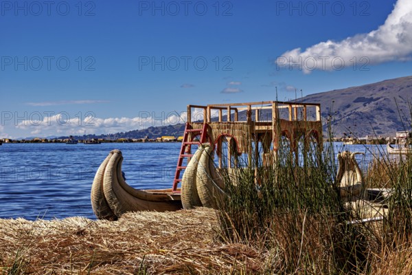 A traditional reed boat is lying on the shores of the lake under a cloudy sky, The floating reed islands of the Uros in Lake Titicaca in Peru